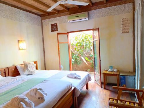 a bedroom with two beds and a large window at Ireenkevin guesthouse in Luang Prabang