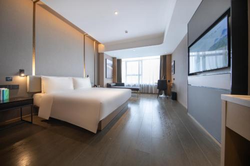 a bedroom with a large white bed and a tv at Atour Hotel Guangzhou Liwan District Jiaokou in Guangzhou