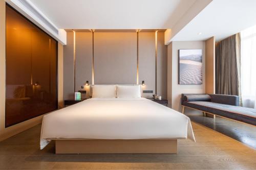 a bedroom with a large white bed and a couch at Atour Hotel Guangzhou Liwan District Jiaokou in Guangzhou