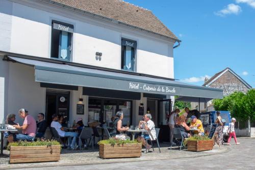 a group of people sitting at tables outside of a building at Auberge de la boucle in Moisson