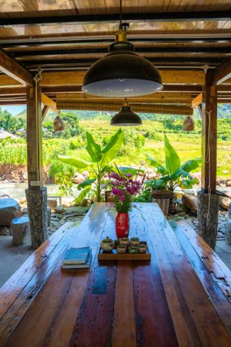 a wooden table with a vase of flowers on it at Clubhouse Mebayluon Paragliding--Homestay, Bay dù lượn, Bể bơi, Sân cỏ, Cắm trại in Pu Chu Chay