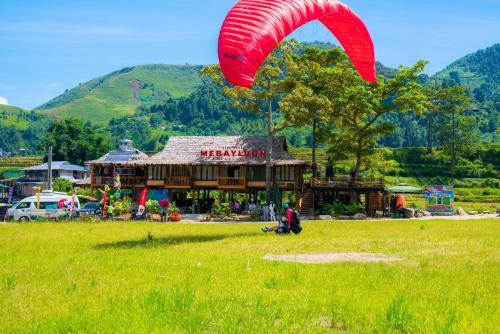 a person flying a red kite in front of a building at Clubhouse Mebayluon Paragliding--Homestay, Bay dù lượn, Bể bơi, Sân cỏ, Cắm trại in Pu Chu Chay