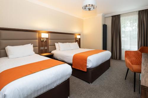 a hotel room with two beds and a chair at Westlands of Pitlochry in Pitlochry