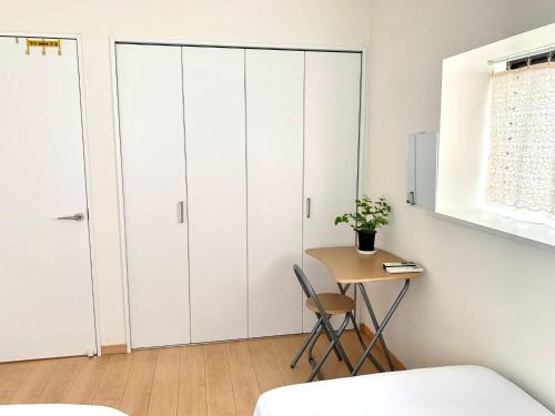 a bedroom with white cabinets and a table with a chair at guest house REST in Kubogayato