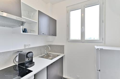 une cuisine blanche avec un évier et une fenêtre dans l'établissement Studio agréable et tout équipé à Montreuil - II, à Montreuil