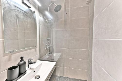 une salle de bain blanche avec un lavabo et une douche dans l'établissement Studio agréable et tout équipé à Montreuil - II, à Montreuil