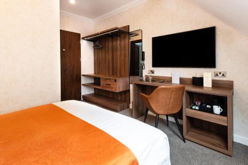 a hotel room with a bed and a desk with a television at Westlands of Pitlochry in Pitlochry
