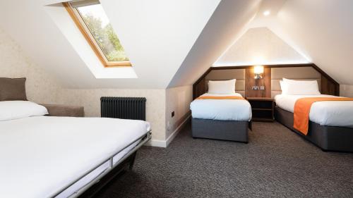 a attic room with two beds and a window at Westlands of Pitlochry in Pitlochry