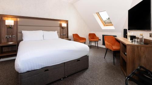 a hotel room with a large bed and a desk at Westlands of Pitlochry in Pitlochry