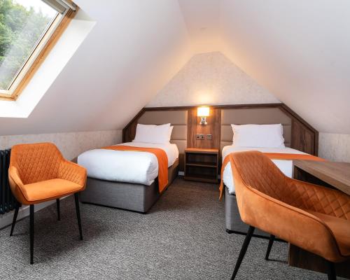 a attic room with two beds and a chair at Westlands of Pitlochry in Pitlochry