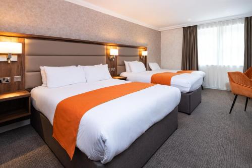 a hotel room with two beds and a chair at Westlands of Pitlochry in Pitlochry