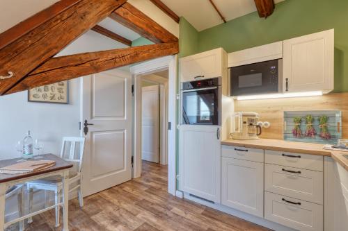 a kitchen with white cabinets and a table and a door at Ferienwohnungen Steinweg 61 in Quedlinburg