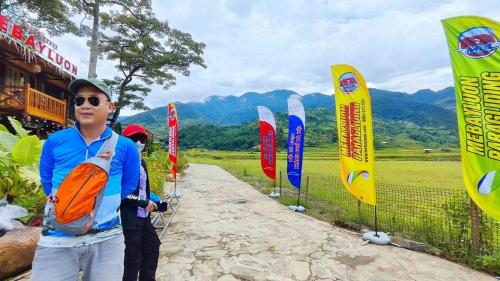 a man standing on a dirt road with flags at Clubhouse Mebayluon Paragliding--Homestay, Bay dù lượn, Bể bơi, Sân cỏ, Cắm trại in Pu Chu Chay