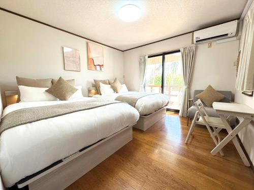 a bedroom with two beds and a desk and a window at The CATAN 石垣島 in Nagura