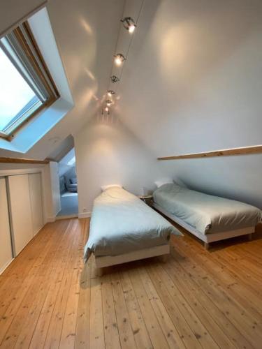 une chambre avec deux lits et une lucarne dans l'établissement L escapade, à Grandcamp-Maisy