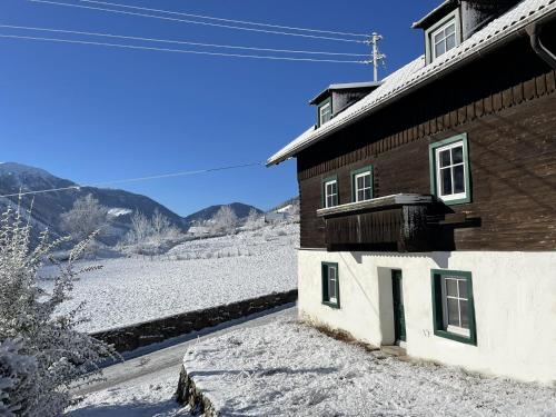 a building with snow on the ground next to a mountain at Das schräge Häusl in Rangersdorf