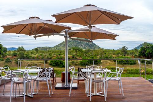 a deck with tables and chairs and umbrellas at Royal Mukumbura Malelane in Malelane