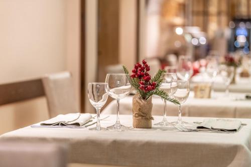 a table with wine glasses and a vase with flowers at Hotel Italo in Madonna di Campiglio