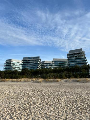 two tall buildings in the background of a sandy beach at Wave Front Sea View 7 Floor in Międzyzdroje