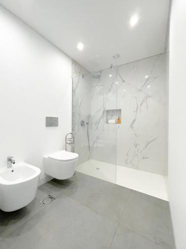 a white bathroom with a sink and a shower at Enchanted Bay in Câmara de Lobos