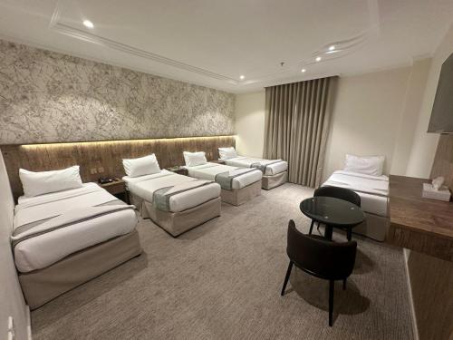a hotel room with two beds and a desk at فندق الخلفاء الماسي الفندقية in Makkah