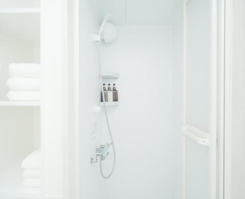 a shower in a bathroom with white walls and a shower at 東京リリアルホテル201 in Tokyo