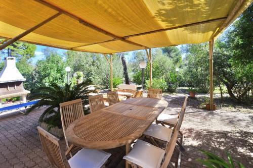 una mesa de madera y sillas bajo una sombrilla amarilla en Villino Saline - Happy Rentals, en Orbetello
