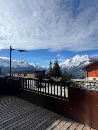 a wooden deck with a view of snow covered mountains at La Rosière centre, appartement 51 m2,3 pièces 2 chambres avec terrasse et parking couvert plein centre de la station, proche des pistes et commerces, ménage compris in La Rosière