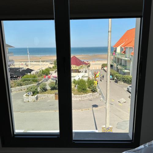 a window with a view of a beach and the ocean at Logis- Hôtel de la Baie de Wissant & Appartements in Wissant