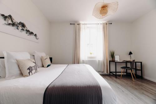 a white bedroom with a large bed and a desk at La Suite D'Hélène - Appartement - 50m2 entre Genève et Chamonix - Parking Privé - Wifi in Scionzier