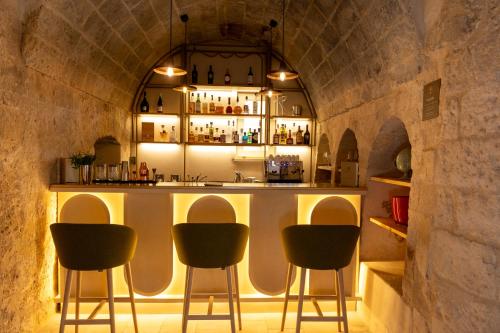 a bar in a stone building with four chairs at Masseria Donna Menga - The Leading Hotels of the World in Torre Lapillo