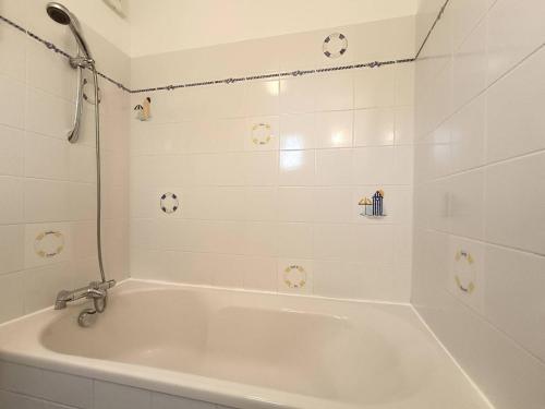 La salle de bains est pourvue d'une baignoire blanche et de carrelage blanc. dans l'établissement Maison avec WIFI jardin à 480m de la plage à Ploumanac'h PERROS-GUIREC - Réf 315, à Perros-Guirec