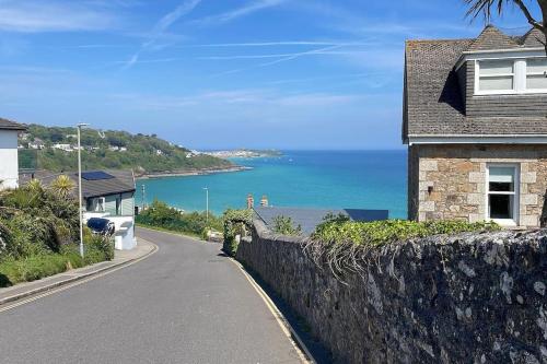 a house on the side of a road next to the ocean at The Lookout in Carbis Bay