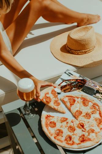 a woman holding a glass of beer next to a pizza at Olé Tropical Tenerife Adults Only in Playa de las Americas