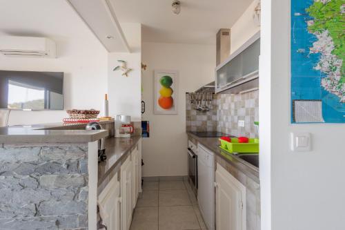 - une cuisine avec des placards blancs et un mur en pierre dans l'établissement La Paolina - Appt 4p avec vue sur golfe de Calvi, à LʼÎle-Rousse