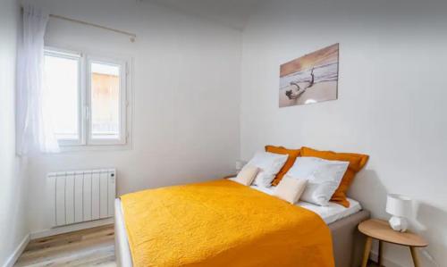 - une chambre blanche avec un lit et une couverture orange dans l'établissement Iris la ciotat, à La Ciotat
