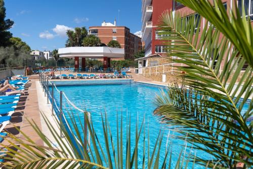 a large swimming pool with people sitting on lounge chairs at Seramar Hotel Luna Park Adults Only in El Arenal