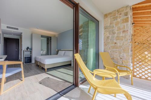 a room with yellow chairs and a table and a bed at Relais Ca Bago' -adults only in Costermano sul Garda