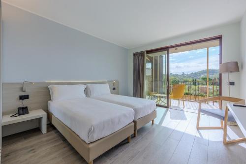 a white bedroom with a bed and a balcony at Relais Ca Bago' -adults only in Costermano sul Garda