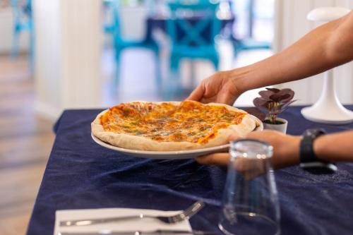 a person holding a plate with a pizza on a table at Seramar Hotel Luna Park Adults Only in El Arenal