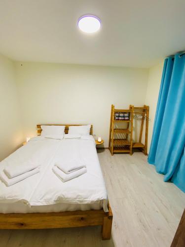 a bedroom with a bed with white sheets and a blue curtain at Dez Guest House, Margahovit, Lori in Margahovit