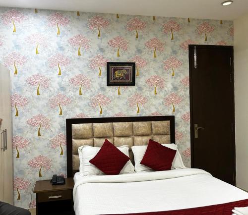 a bedroom with a bed with red pillows and a floral wallpaper at Hotel Nirvana Suites in New Delhi