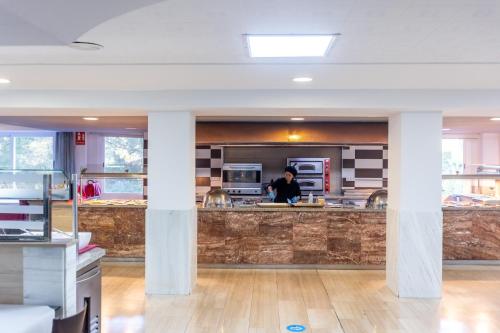 a man standing in a kitchen with columns at Seramar Hotel Luna Park Adults Only in El Arenal