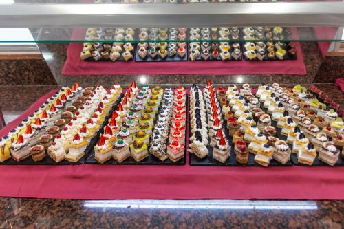 a display case filled with different types of cakes at Seramar Hotel Luna Park Adults Only in El Arenal