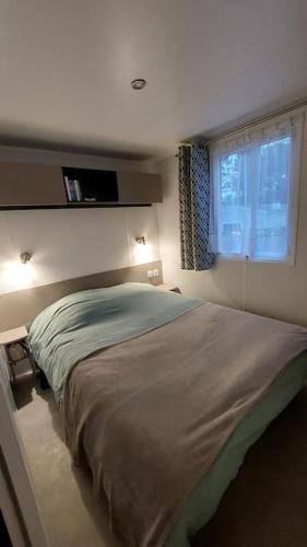 une chambre avec un grand lit avec une fenêtre dans l'établissement Mobilhome 3 chambres TV-WIFI-Lave-linge, à Pont-Aven