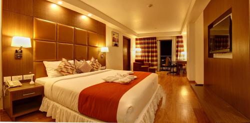 a hotel room with a large bed and a television at The Atrium Boutique Hotel in Mysore