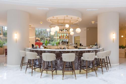 a bar in a lobby with white stools at Ramada by Wyndham Bucharest Otopeni Airport in Otopeni