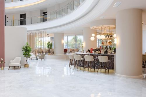 a lobby with a bar with stools and chairs at Ramada by Wyndham Bucharest Otopeni Airport in Otopeni