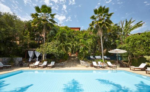 ブジオスにあるPortoBay Búziosの椅子とヤシの木のあるプール
