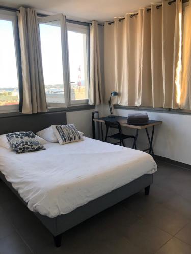 - une chambre avec un lit et une table avec des fenêtres dans l'établissement Tout confort Toulon centre appartement 3 chambres, vue sur la Rade, à Toulon